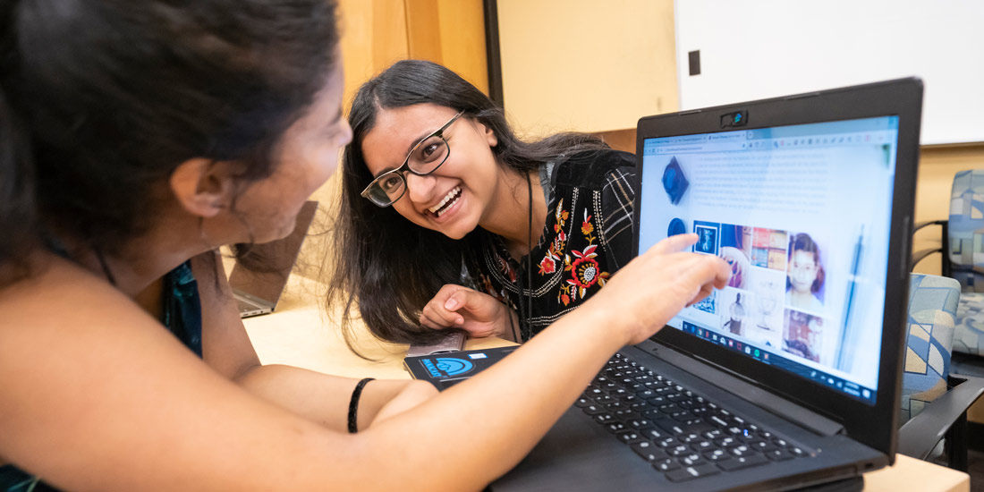 Female students viewing a laptop screen as part of CS KickStart