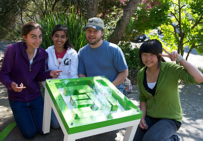 Young makers Pearl Holmes, Jahnavi Kalpathy and Hana Chuang display their “Habitable”—a table that also functions as a hamster habitat—with mentor Joshua Seaver. TONY DeROSE PHOTO