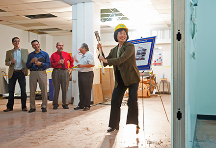 Tsu-Jae King Liu opening a wall with a sledgehammer at the groundbreaking for the TI Electronic Design Lab