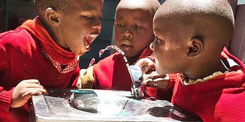 Kenyan children drinking water from a fountain