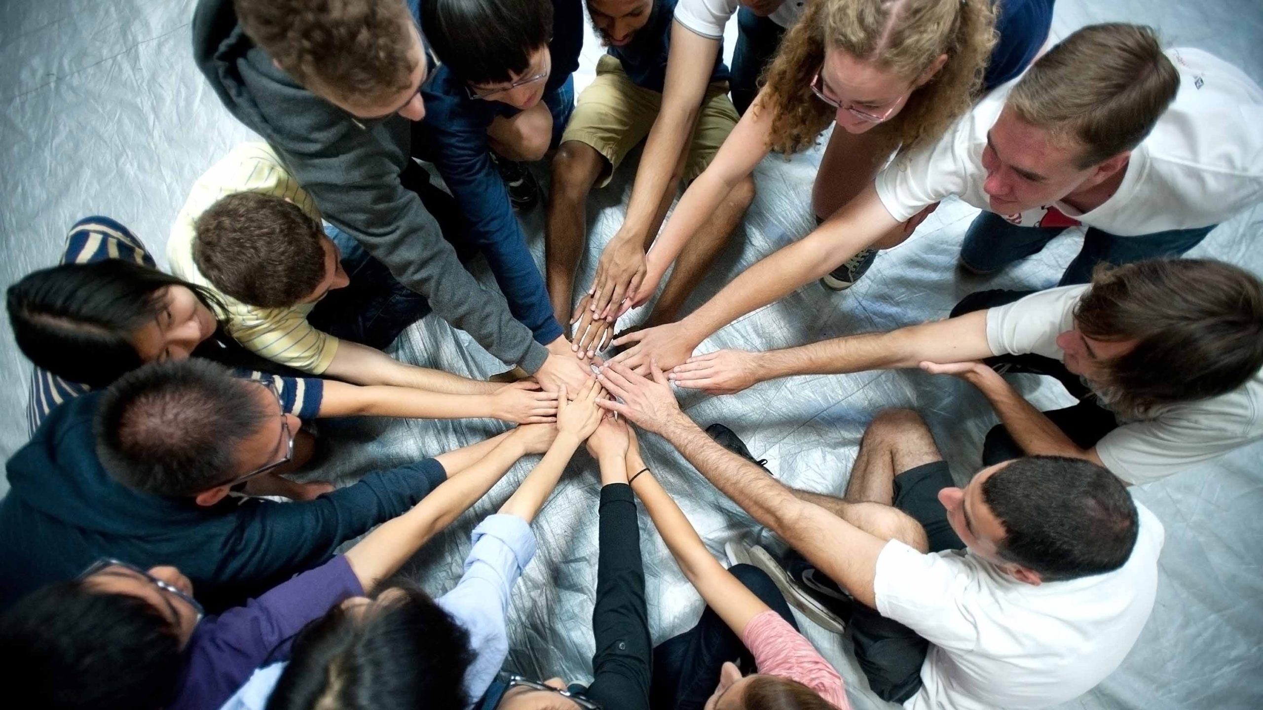 Students forming a circle and joining hands in the center.