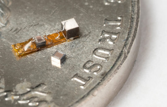 Neural dust components are displayed atop a dime