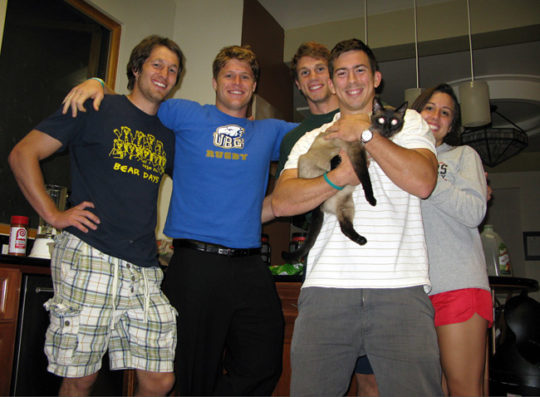 Muhn, holding a cat, with some of his six rugby-playing housemates