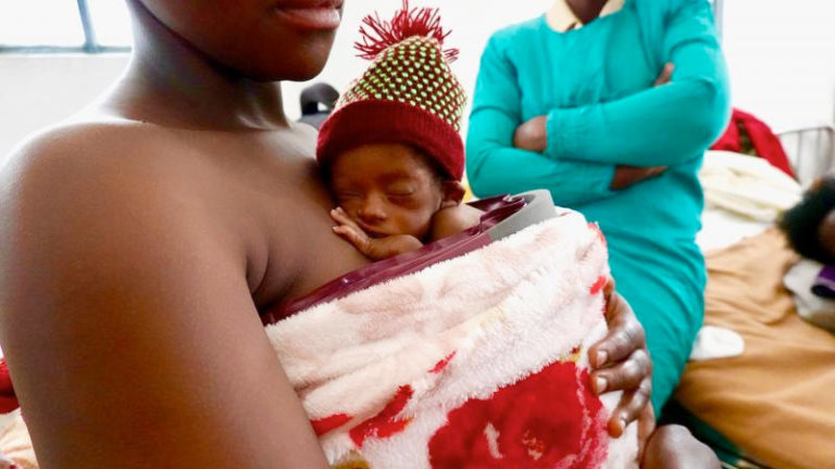 A newborn infant receives supplemental warming while getting skin-to-skin contact with the mother