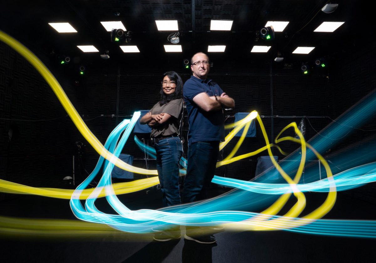 Light trails encircle Yuka Minton and professor Michael Yartsev in their fully automated bat flight room.