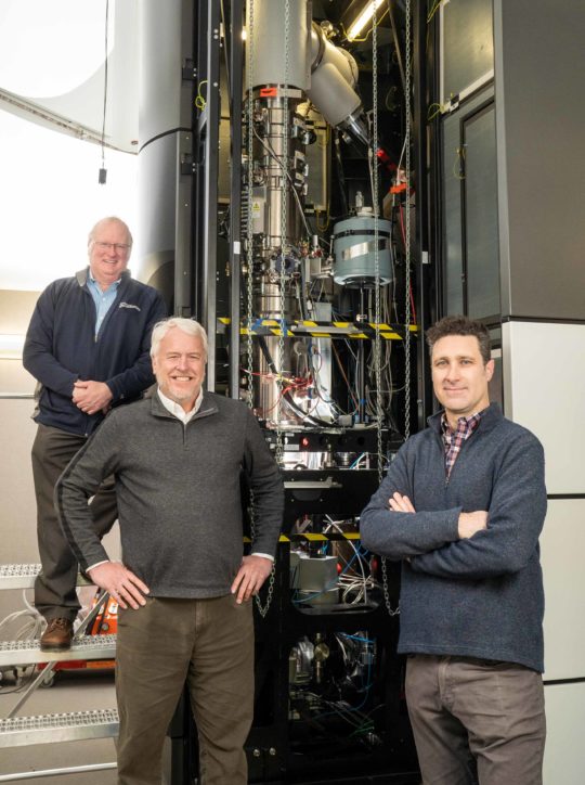 Professors Daryl Chrzan, Mark Asta and Andrew Minor standing by the TEAM I electron microscope