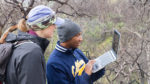 Students check data on a laptop during field research on biodiversity