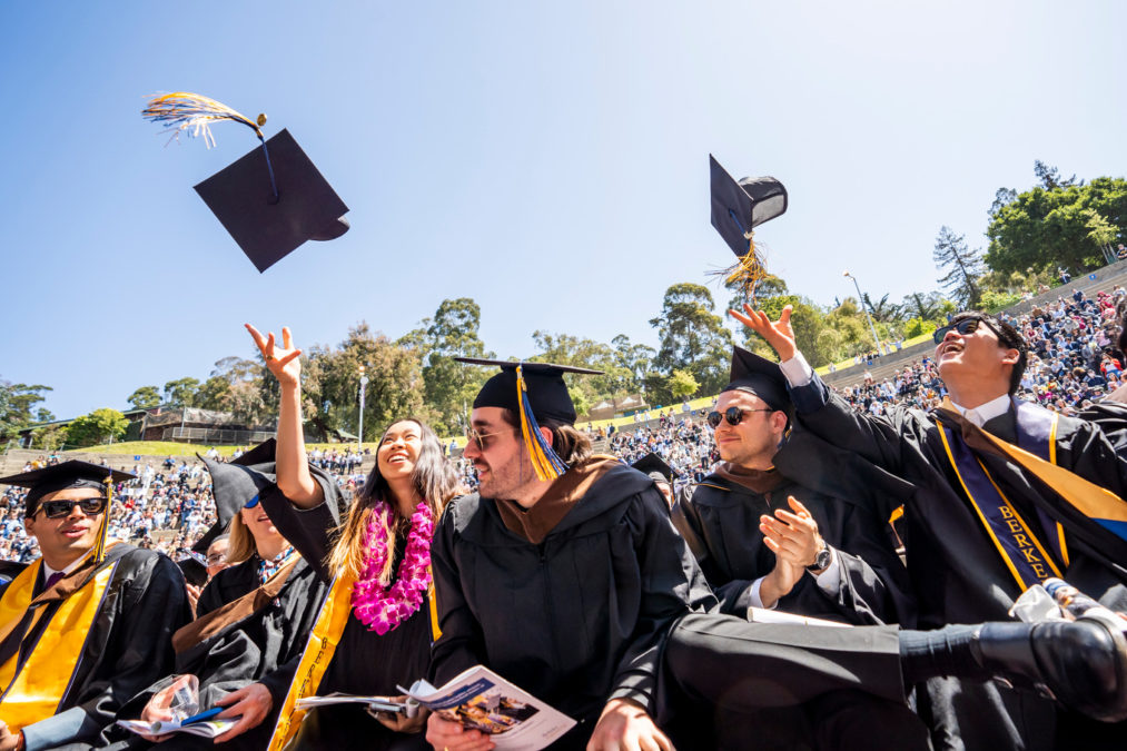 Masters graduates throw their mortar boards in the Greek Theatre