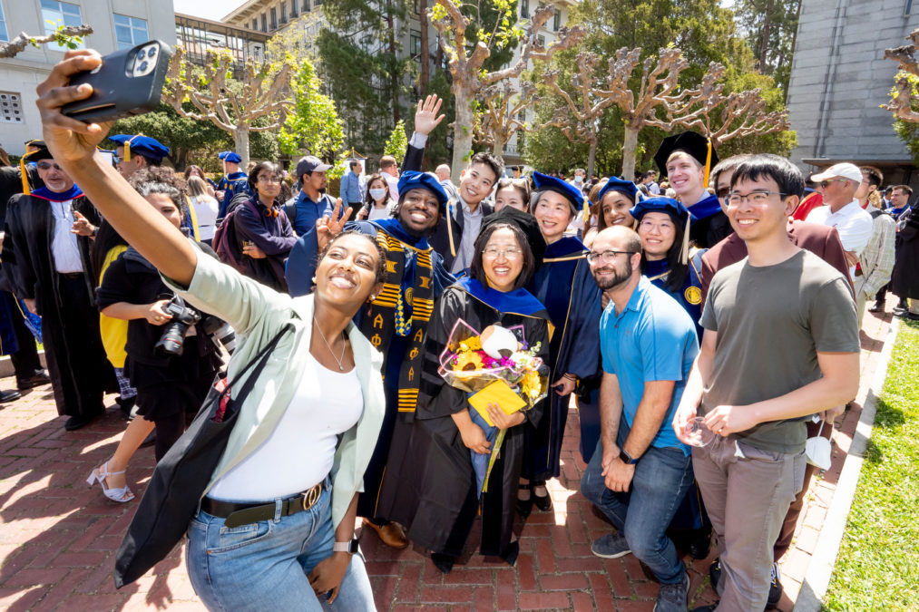 Graduates pose for a selfie beneath the Campanile