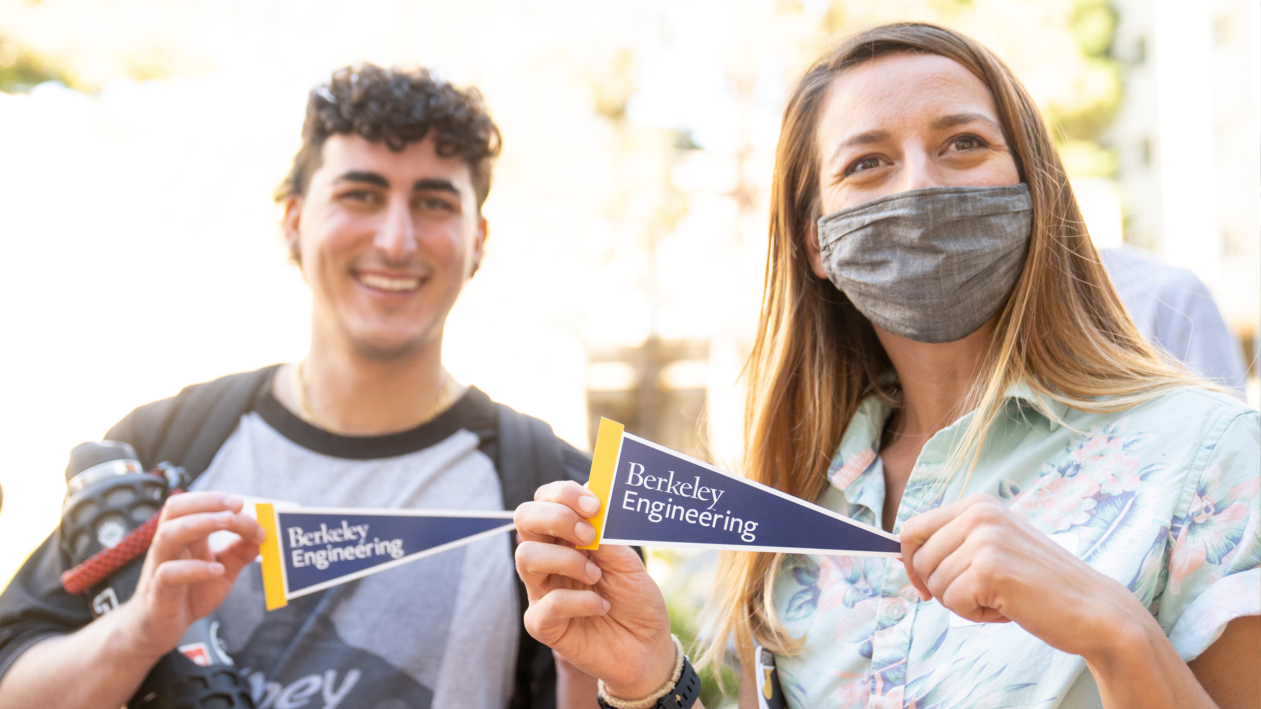 Berkeley Engineering student and staff member holding Berkeley engineering pennants and smiling