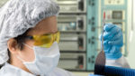 Lab technician in clean room holding a silicon wafer