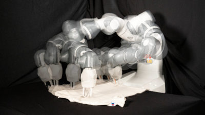 Robot arms (seen here in multiple exposures) folding towels using the SpeedFolding method.