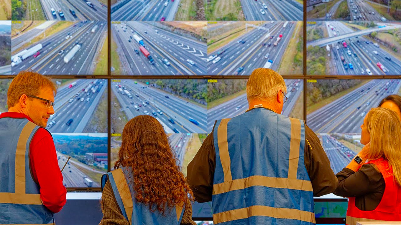 Researchers viewing multiple video screens showing field test of AI-powered cruse control system