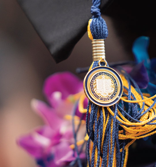 UC Berkeley tassel on graduation cap, with flowers in the background