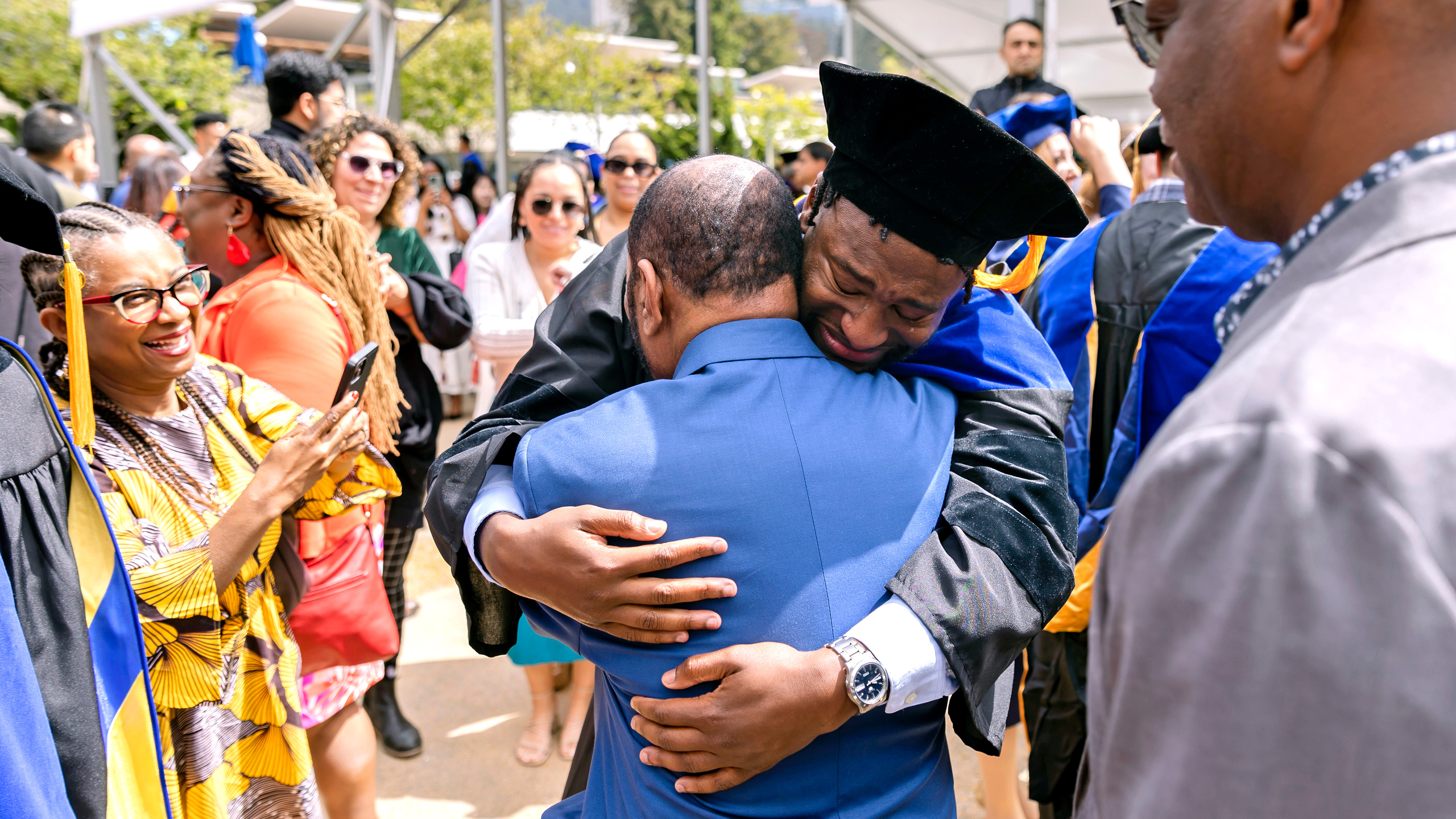 An engineering Ph.D. graduate celebrates with loved ones outside Zellerbach Hall following the Class of 2023 Doctoral Commencement .