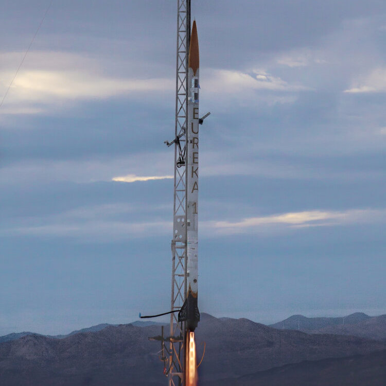 An image of the Eureka-1 rocket on a launchpad with fire spurting out.