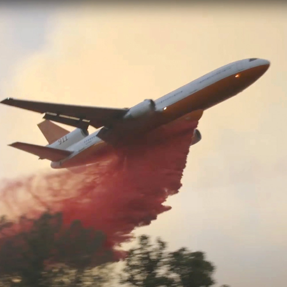 Plane dropping fire retardant on wildfire