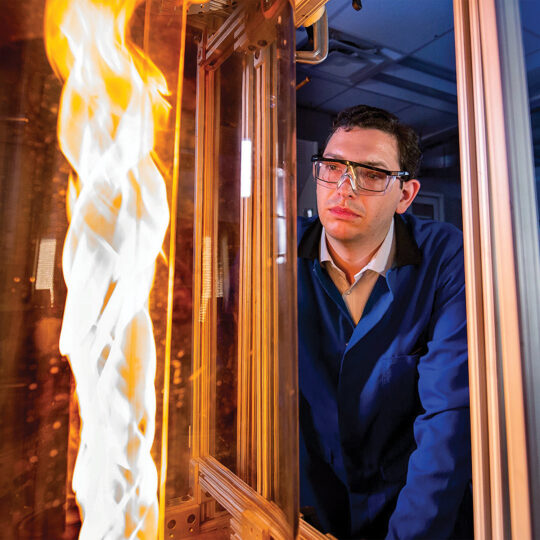 Man watching flames through window in lab