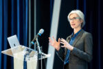 Jennifer Doudna speaks on stage while standing behind a podium and laptop