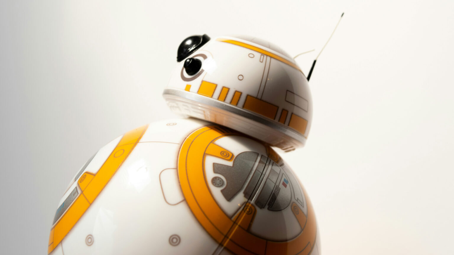 Image of BB-8, a robot with a dome-shaped head and spherical body colored white with orange and silver geometric accents, seen in Star Wars films.