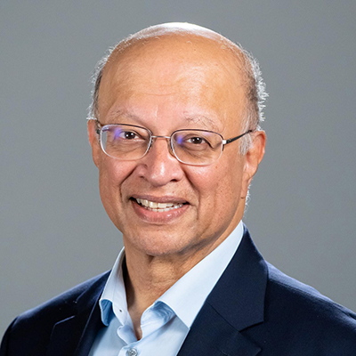 Headshot of Ashok Gadgil in a light blue shirt and dark blue jacket in front of a gray background
