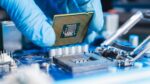 Close-up of a blue-gloved hand constructing a microchip.