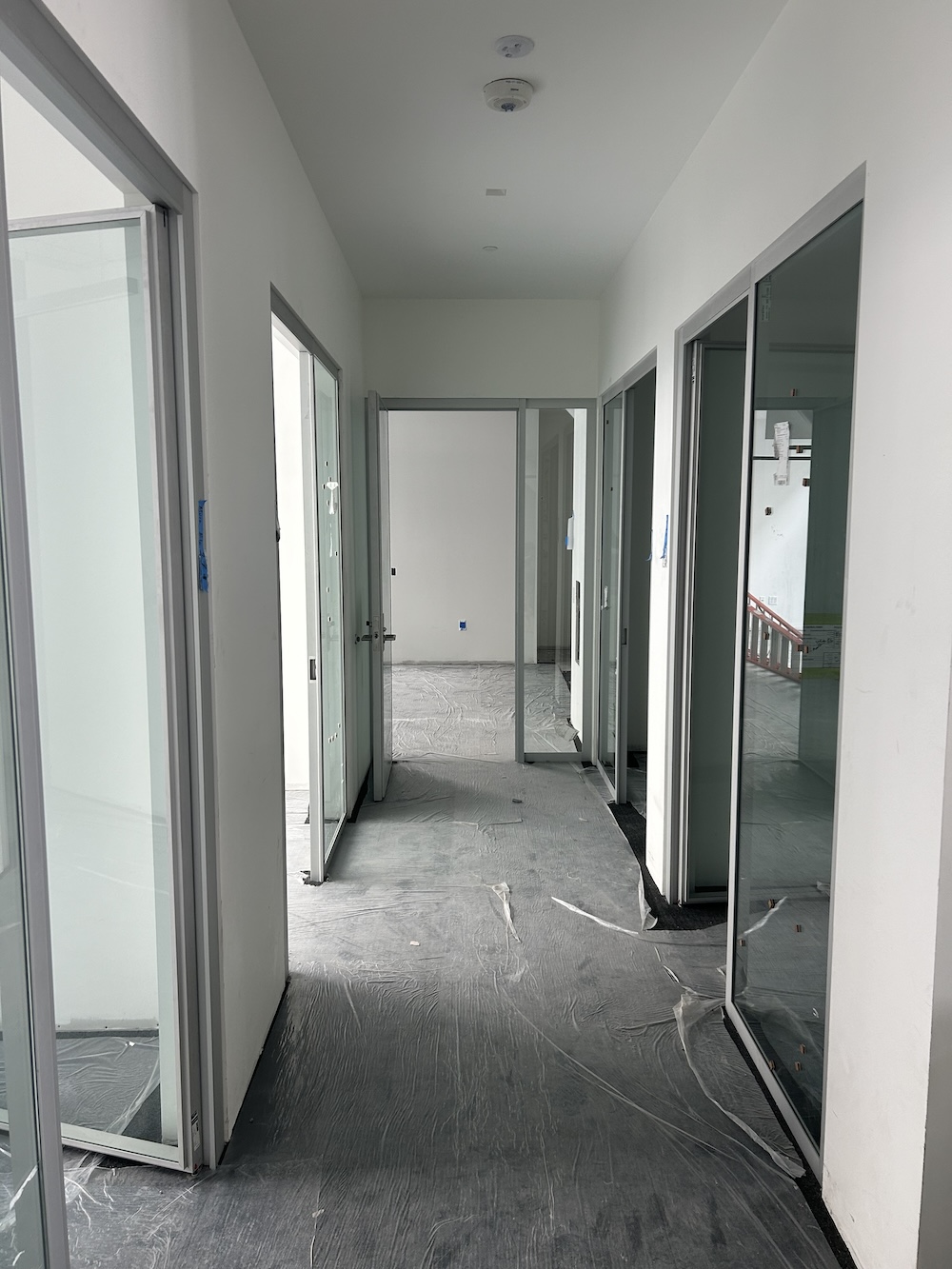 hallway with unfinished floor and doors and glass windows up