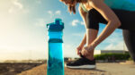 Runner tying her shoe next to a bottle of water.
