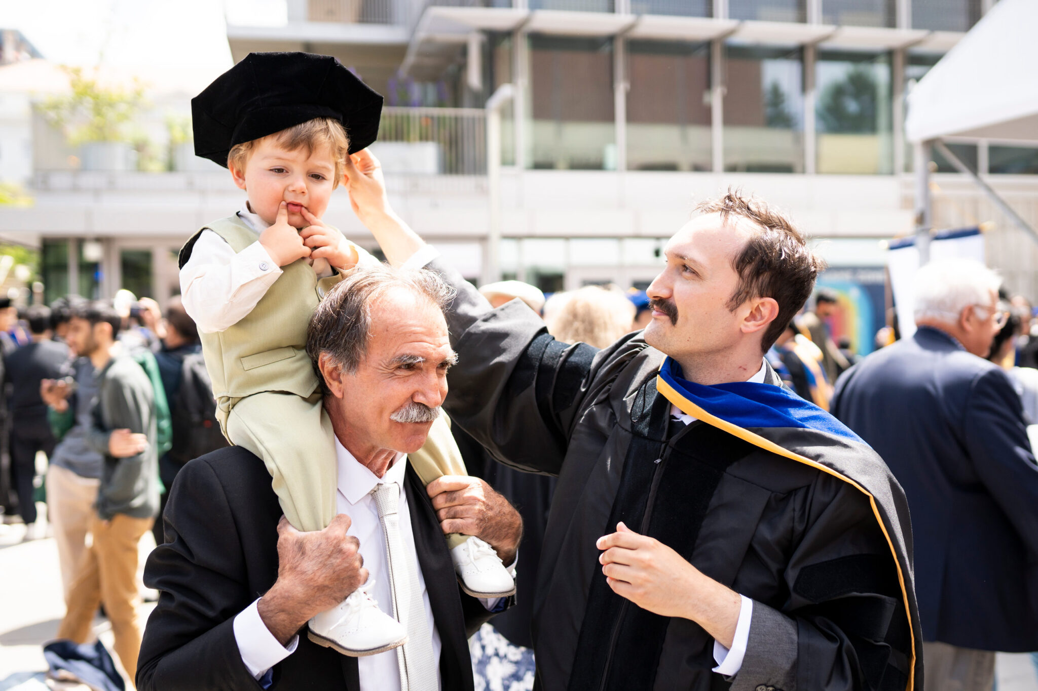 A child dons his father's mortarboard following Doctoral Commencement