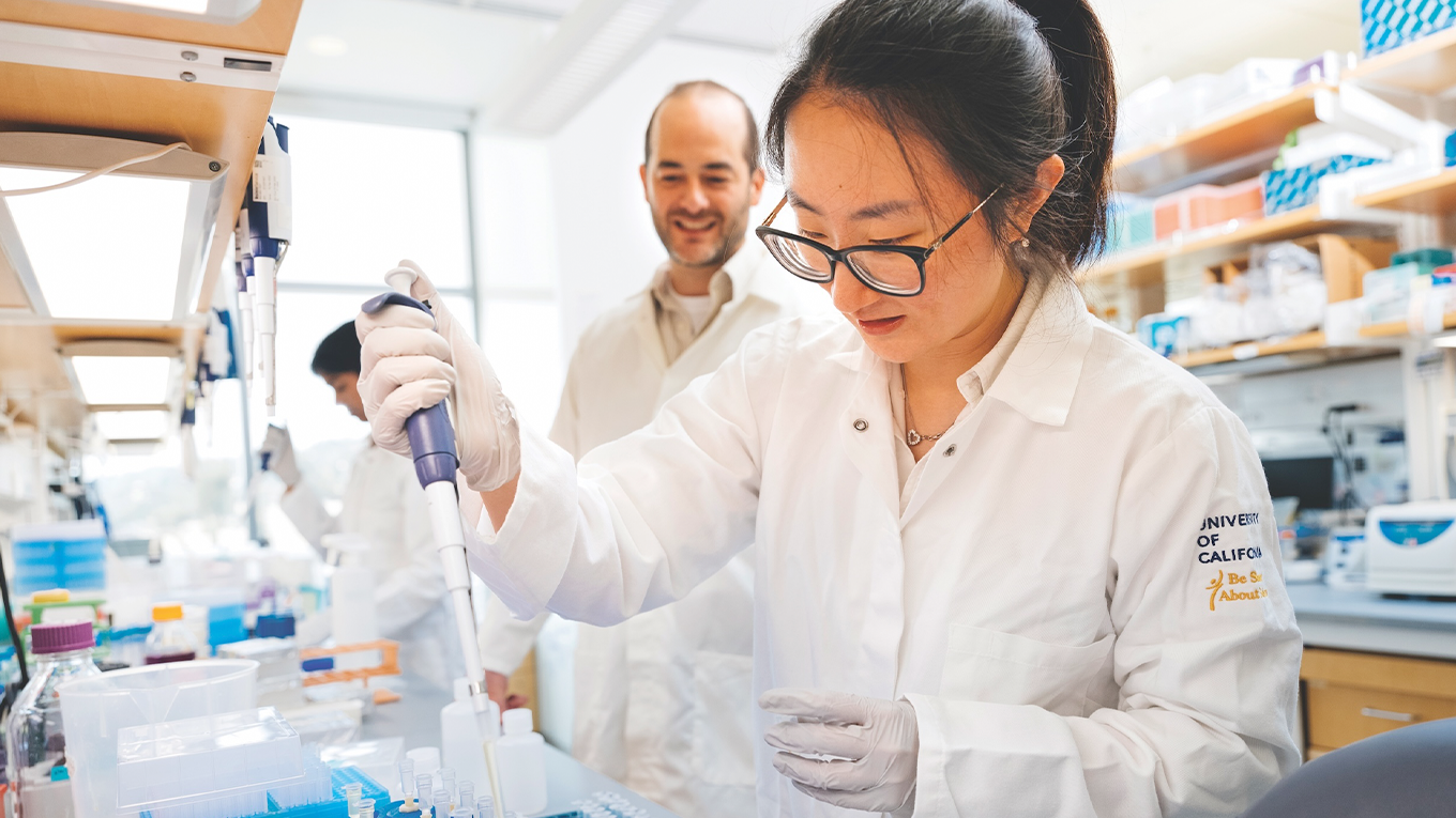 woman in a white coat pipette liquid into a tube